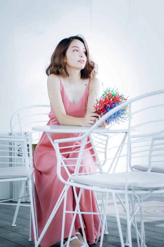 Woman in salmon pink dress sitting at outdoor white table