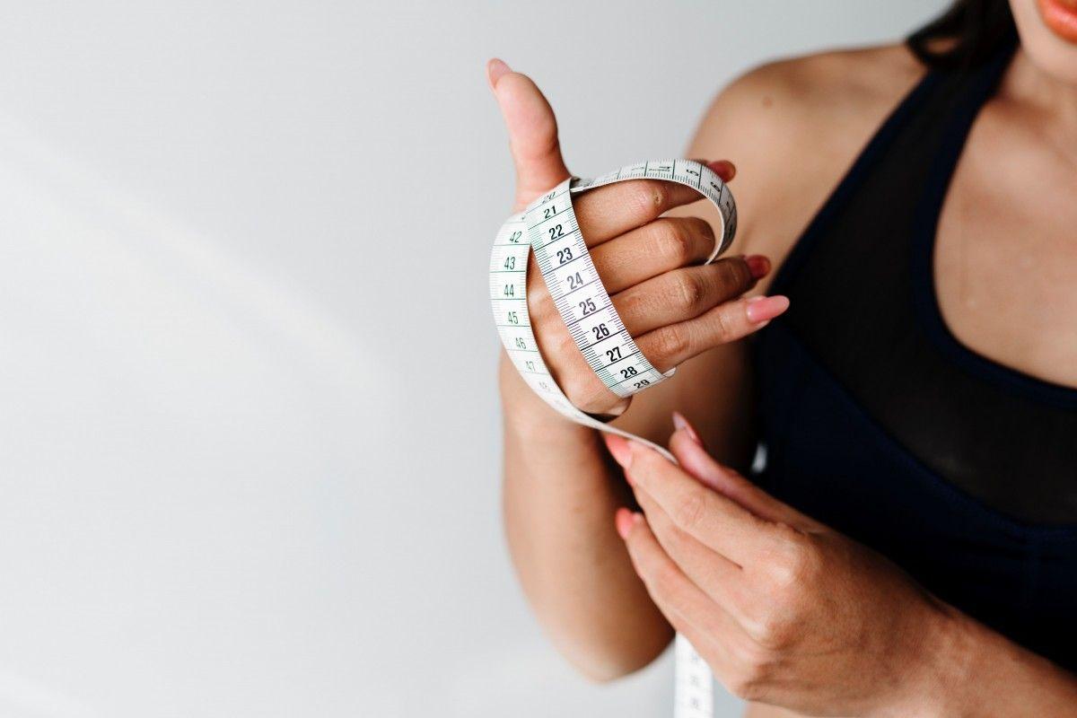 Woman with black top holding soft tape measure in her hand